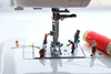 A staged photographic print of mini figures working on sewing machine by New Zealand artist Adam Popovic, available at The Little Gallery Tairua